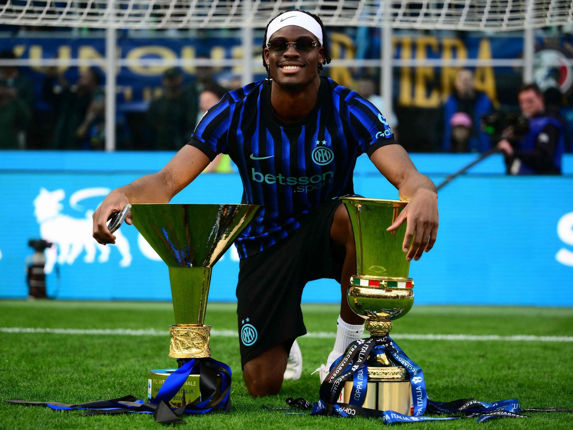 Yann Aurel Bisseck posiert mit Pokal- und Meister-Trophäe auf dem Platz.