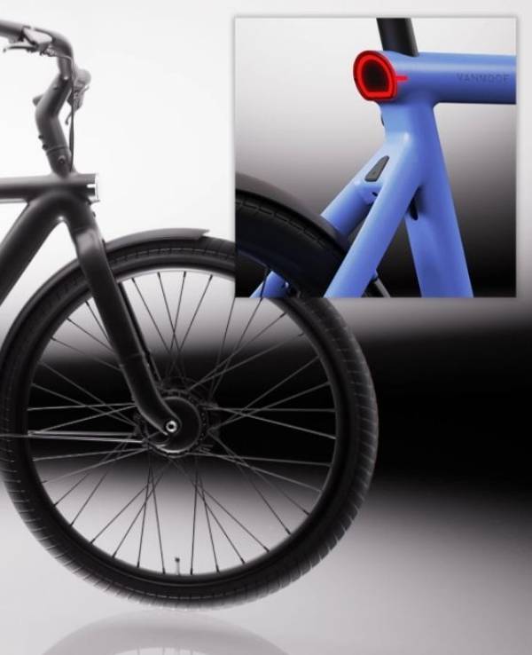 VanMoof S6 E-Bike in der Seitenansicht in der Farbe Drift Black vor hellem Hintergrund, mit Detailaufnahme des nahtlos in den Aluminiumrahmen integrierten Rücklichts in der Farbe Electric Blue – sichtbar auch das integrierte Frontlicht am Vorderrad.
