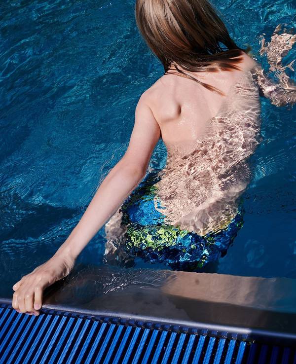 Ein Kind hält sich am Rand eines Schwimmbeckens fest