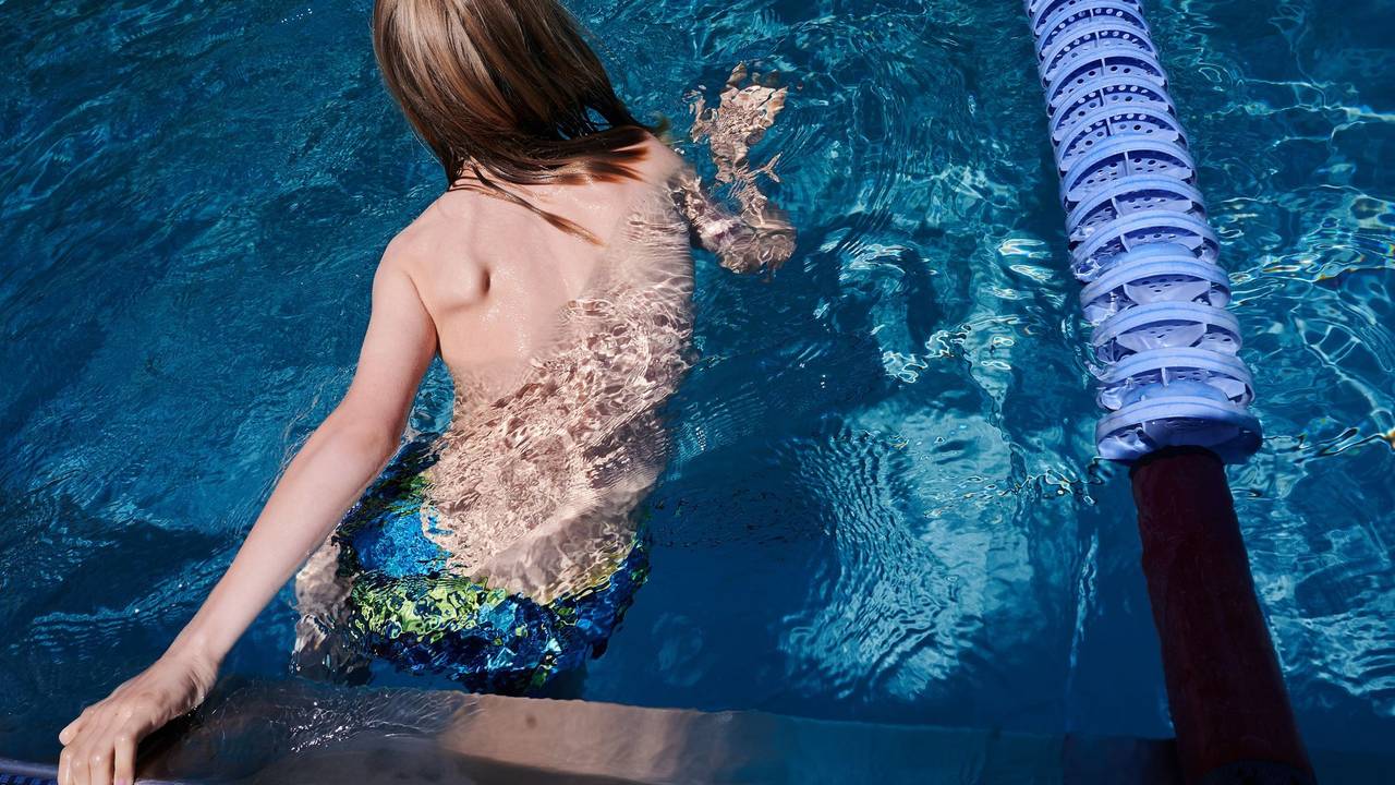 Ein Kind hält sich am Rand eines Schwimmbeckens fest