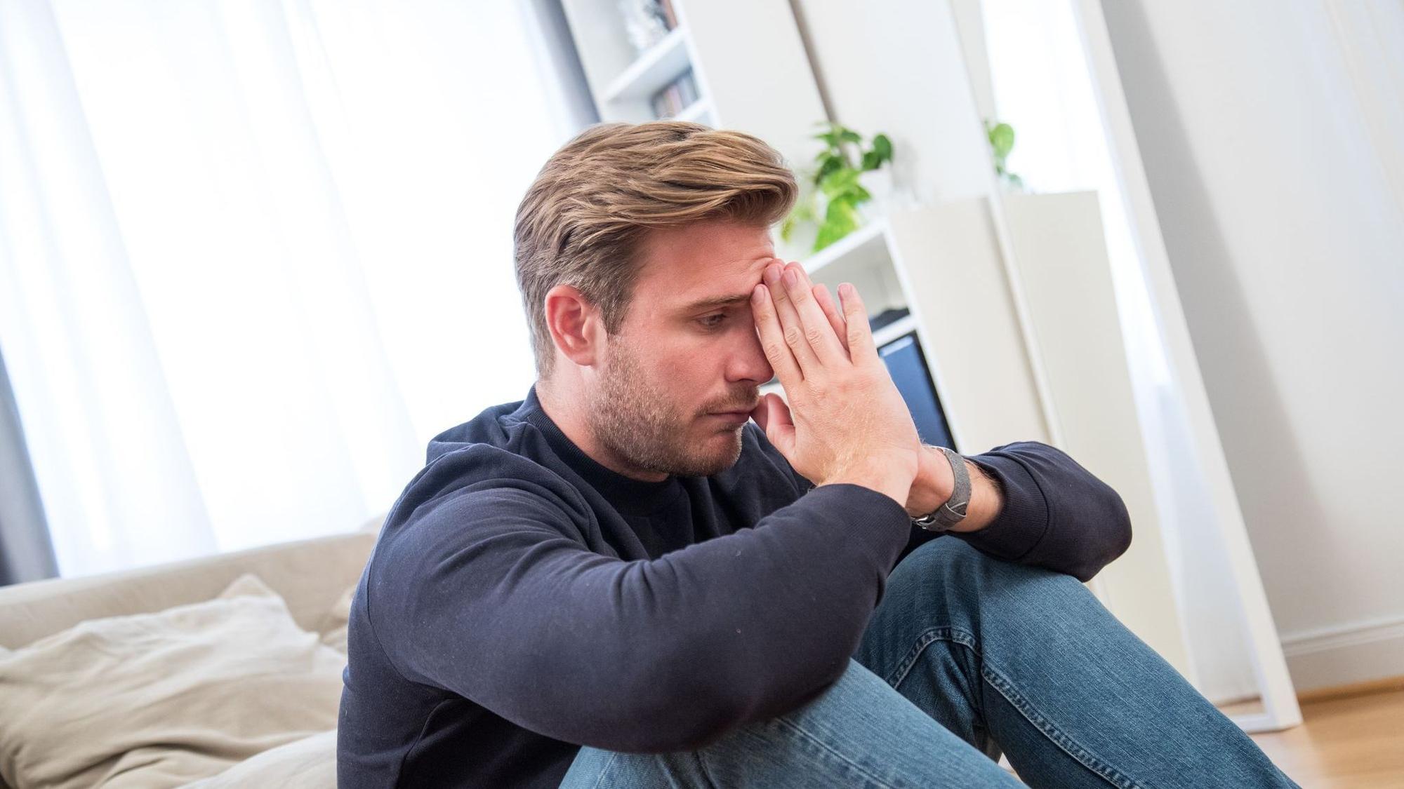 Ein junger Mann gestresst in einem Wohnzimmer