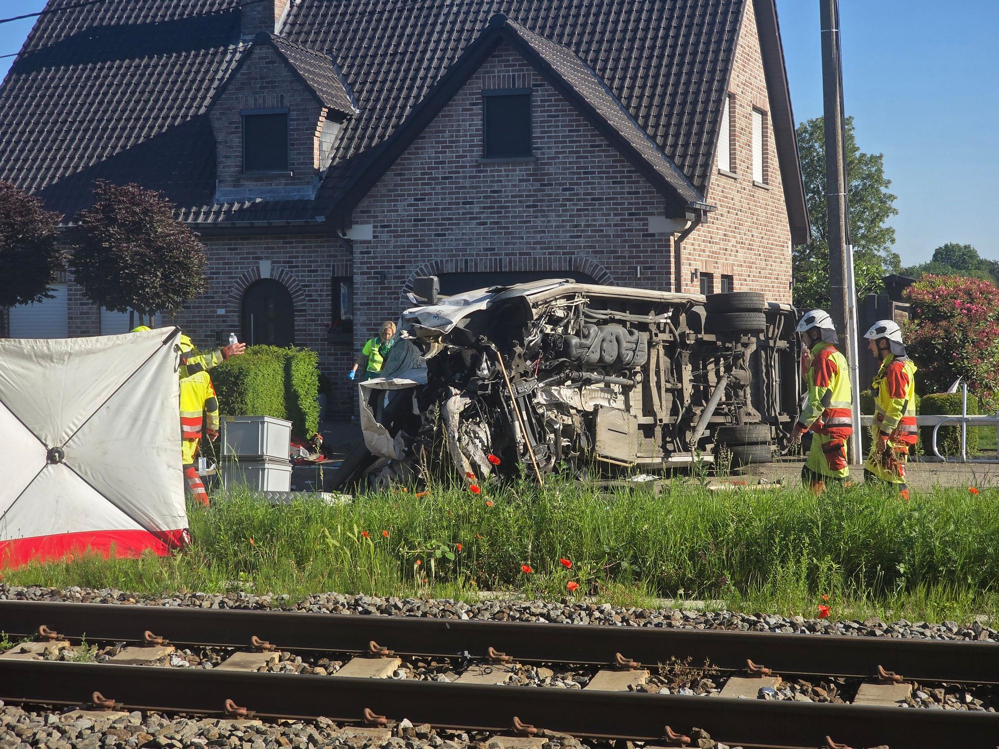 Rettungskräfte sind bei einem Unfallort im Einsatz, nachdem ein Zug mit einem Schulbus am Bahnübergang Vierhuizen in Buggenhout zusammengestoßen war.