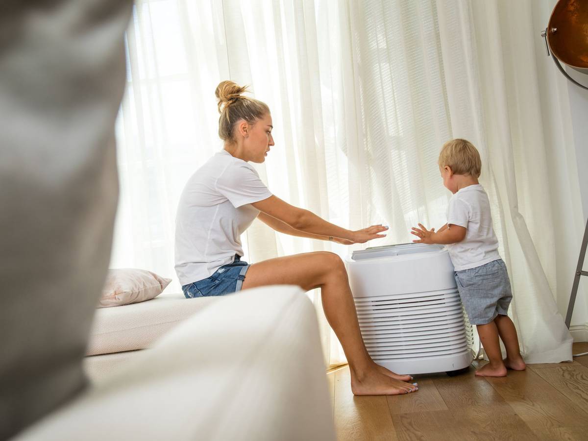 Eine Mutter und ihr kleiner Sohn stehen an einem Klimagerät