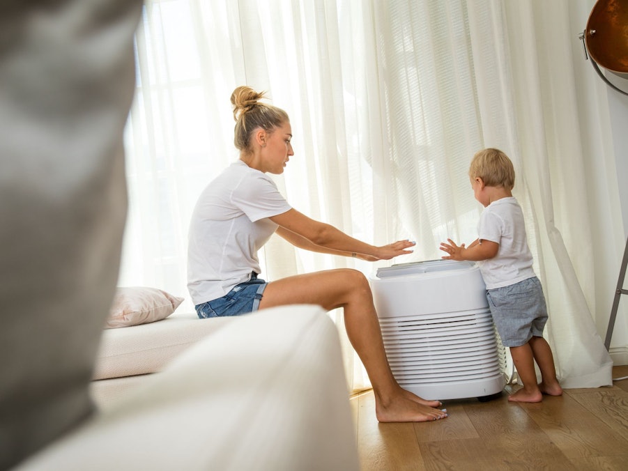 Eine Mutter und ihr kleiner Sohn stehen an einem Klimagerät