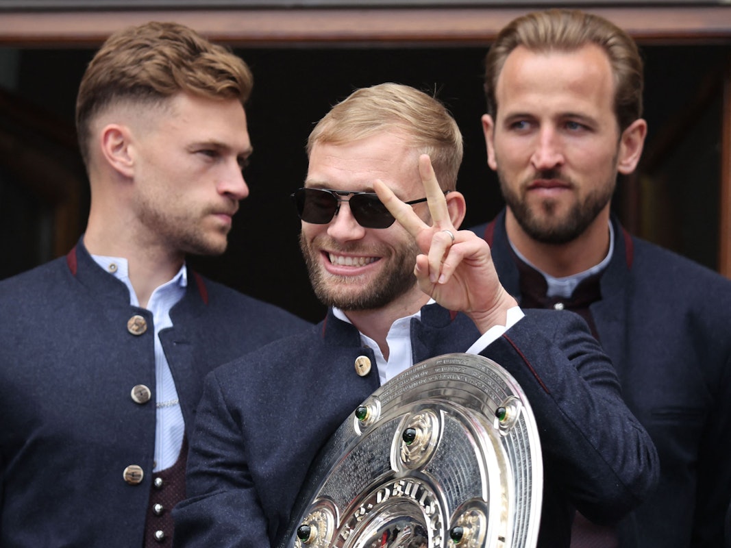 Konrad Laimer vom FC Bayern feiert mit der Meisterschale. DFB-Profi Joshua Kimmich und England-Kapitän Harry Kane stehen dahinter.