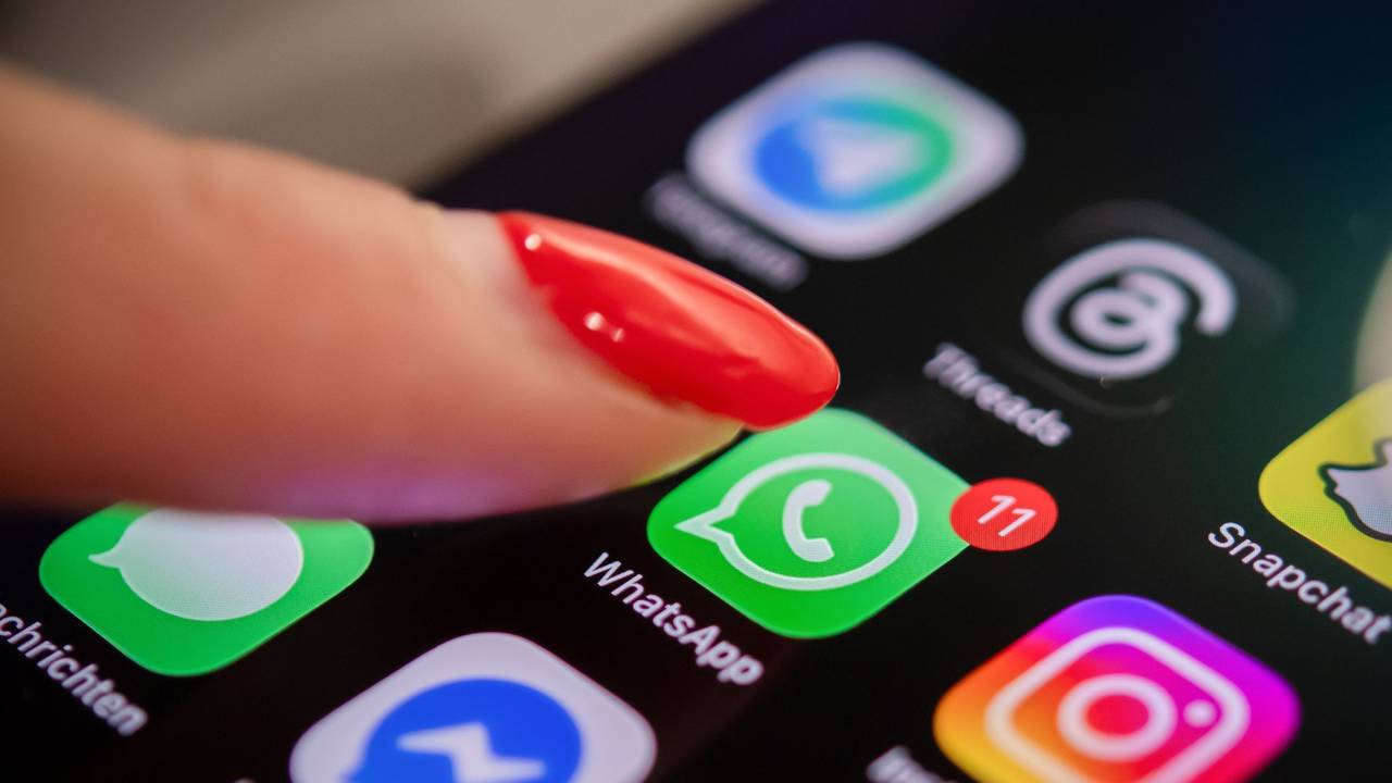 Eine Frau tippt auf einem Smartphone auf das WhatsApp-Symbol