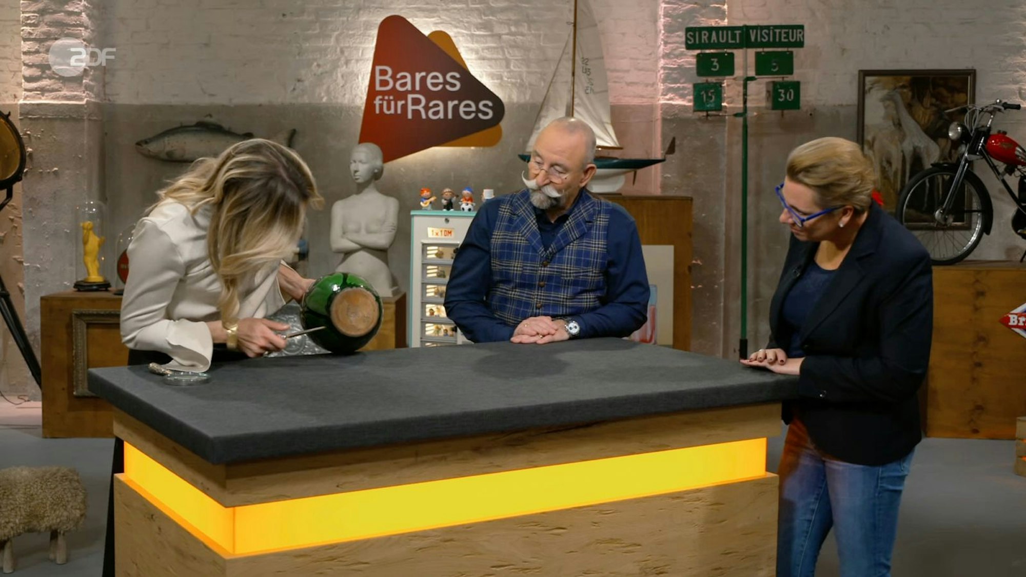 Verkäuferin Lena wurde in der Mittwochsausgabe der ZDF-Trödelshow „Bares für Rares“ bei Horst Lichter enttäuscht: „Leider nicht das, was ich hören wollte“, erwiderte sie nach der Expertise ihrer Jugendstil-Vase. Denn am Boden fehlte ein bestimmtes Künstlersignet. Einer Händlerin war das anscheinend nicht wichtig. Sie verdoppelte den Wunschpreis. (Bild: ZDF)