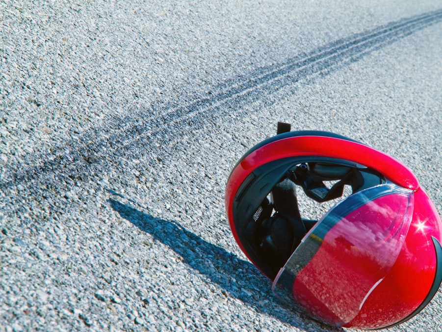 Roter Motorradhelm und Bremsspuren auf Asphalt