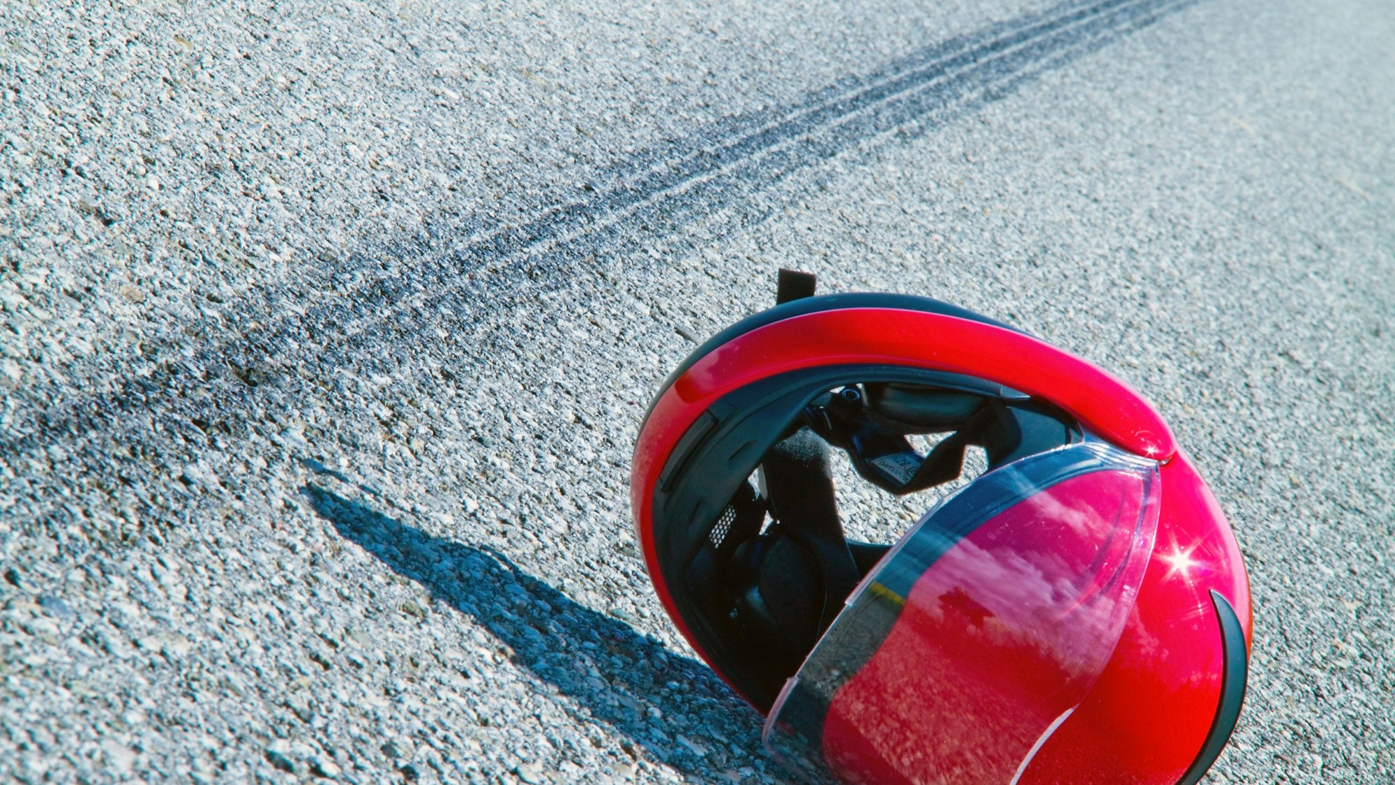 Roter Motorradhelm und Bremsspuren auf Asphalt
