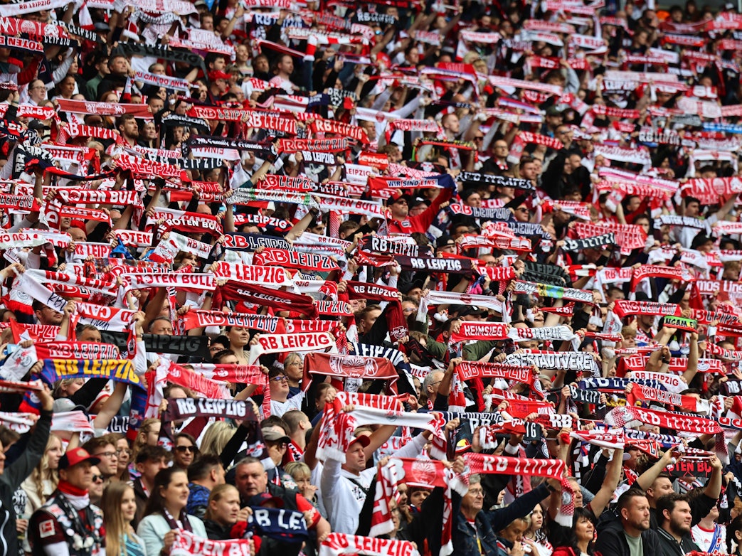 Fans von RB Leipzig halten ihre Schals hoch.