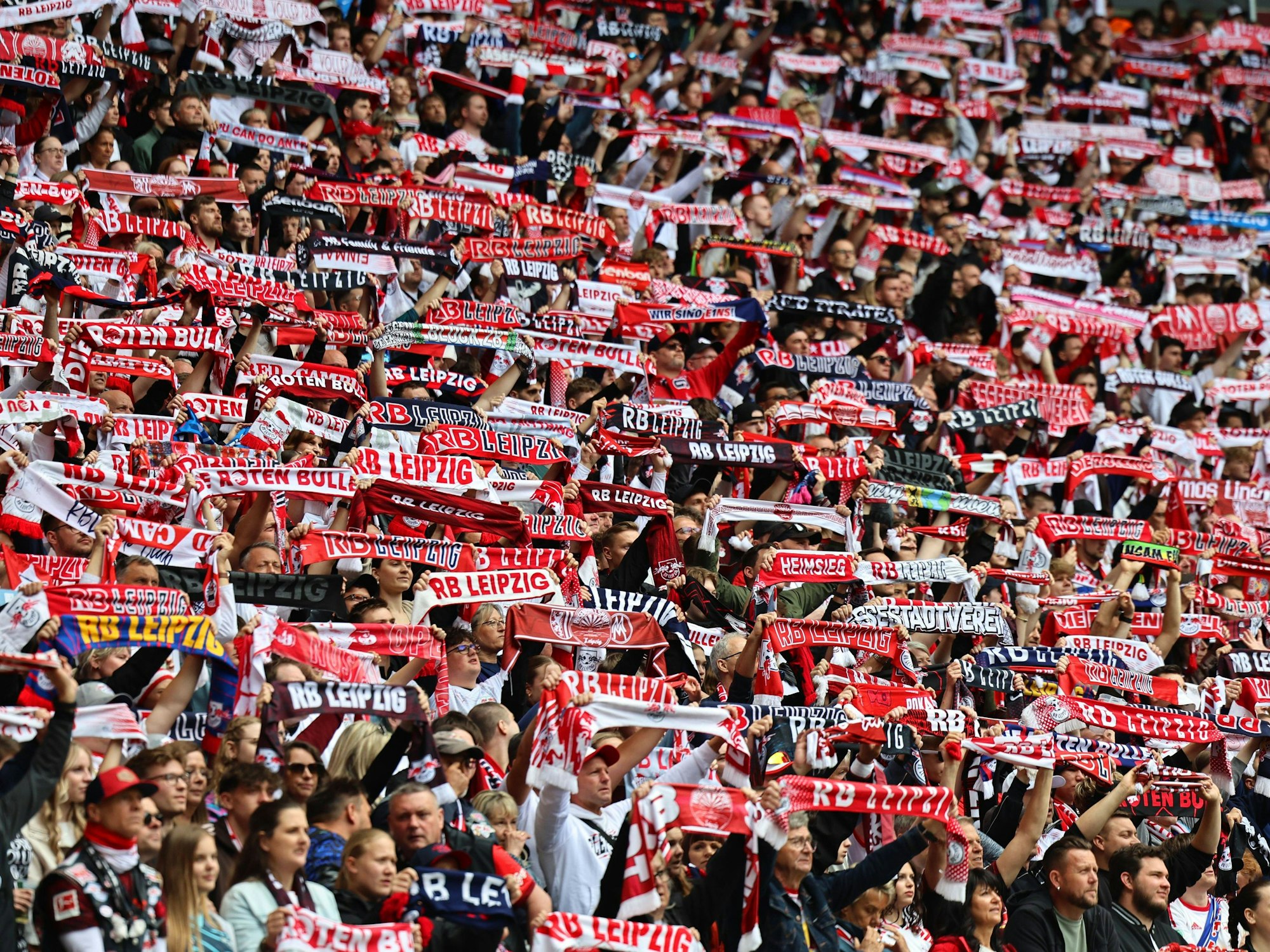 Fans von RB Leipzig halten ihre Schals hoch.