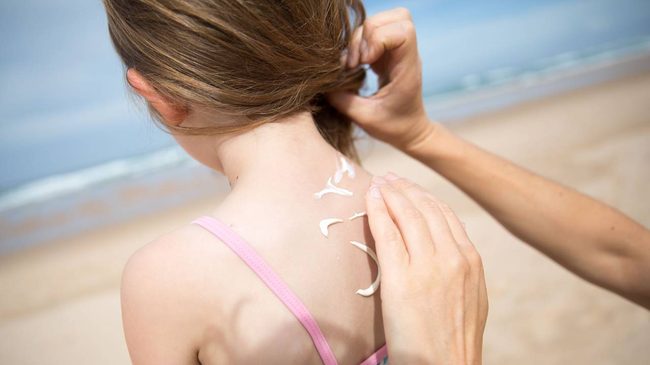 Eine Frau cremt ihre Tochter mit Sonnencreme ein
