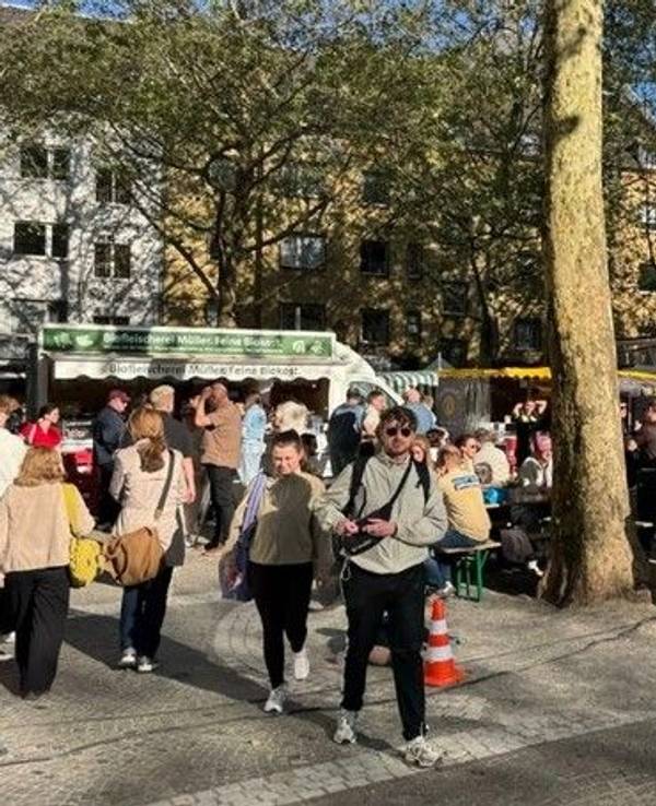 Menschen drängen sich auf einem Platz vor mehreren Marktständen.