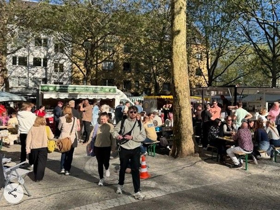 Menschen drängen sich auf einem Platz vor mehreren Marktständen.