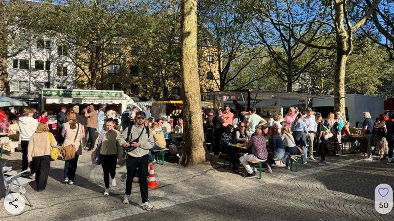 Menschen drängen sich auf einem Platz vor mehreren Marktständen.