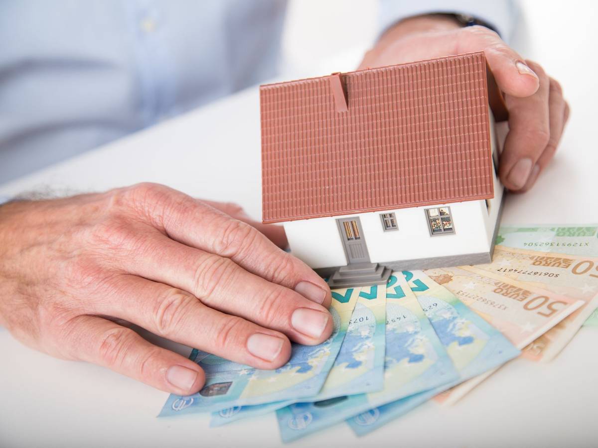 Ein Mann hält das Modell eines Hauses in den Händen