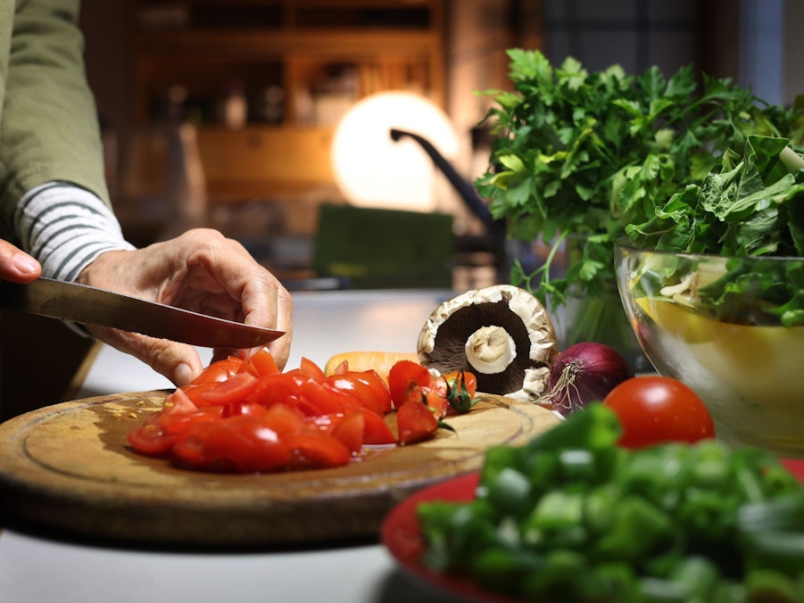 Eine Frau bereitet beim Kochen das Gemüse vor