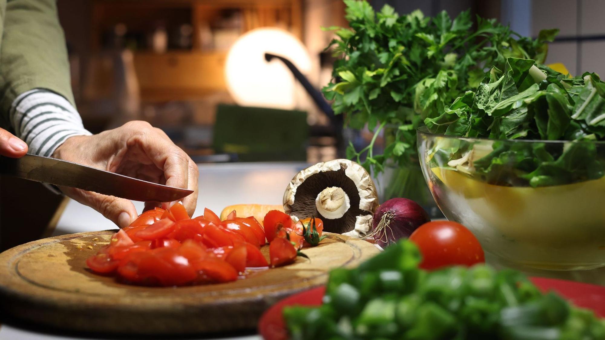 Eine Frau bereitet beim Kochen das Gemüse vor