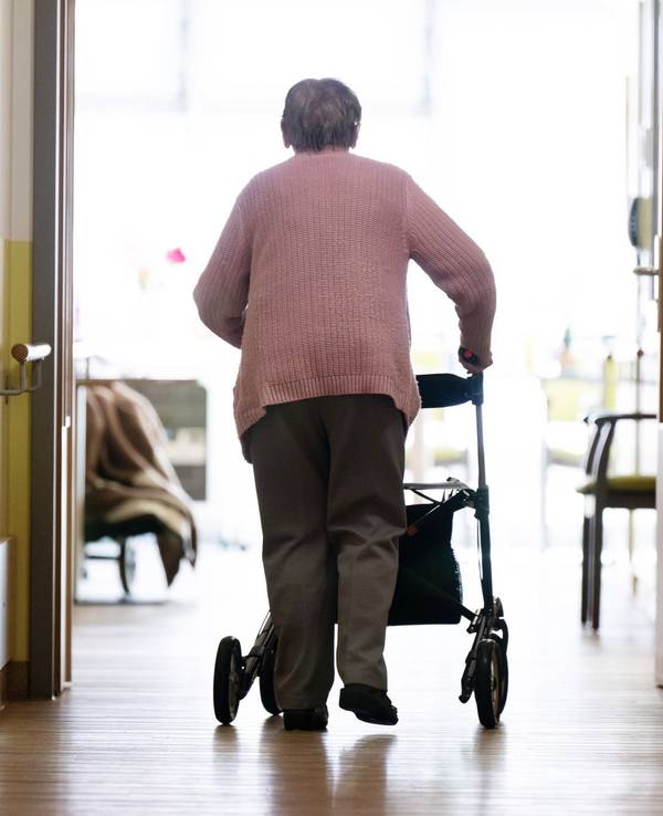 Eine Frau geht mit einem Rollator in einem Altenheim