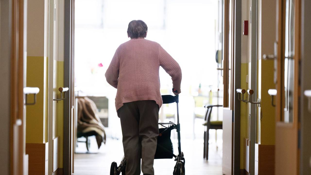 Eine Frau geht mit einem Rollator in einem Altenheim