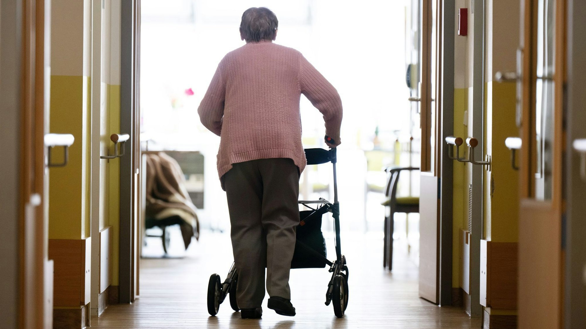 Eine Frau geht mit einem Rollator in einem Altenheim