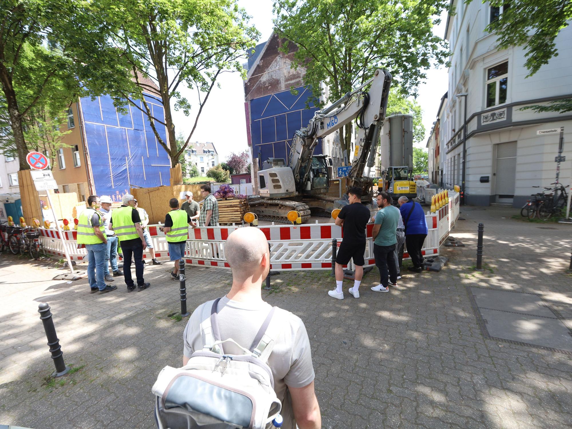 Anwohner und Mitarbeiter von städtischen Ämtern stehen um eine Baugrube.