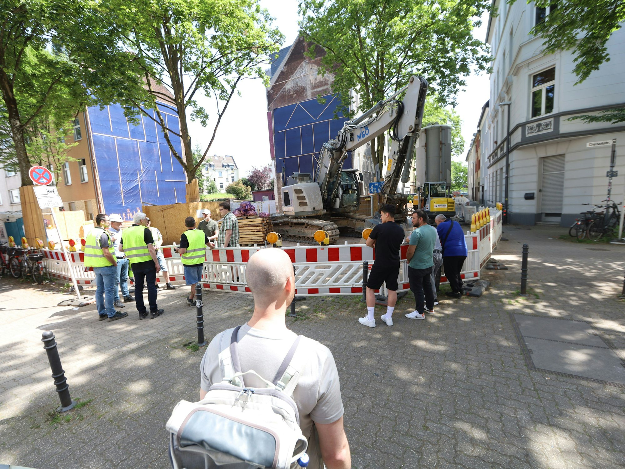 Anwohner und Mitarbeiter von städtischen Ämtern stehen um eine Baugrube.