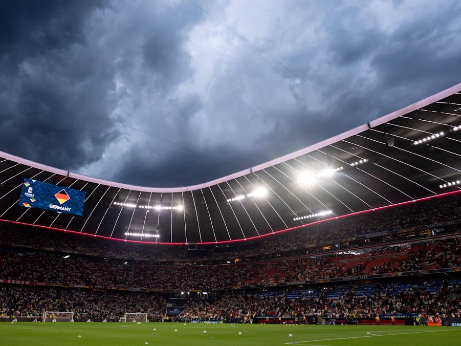 Fußballstadion mit Zuschauern unter dunklem Himmel