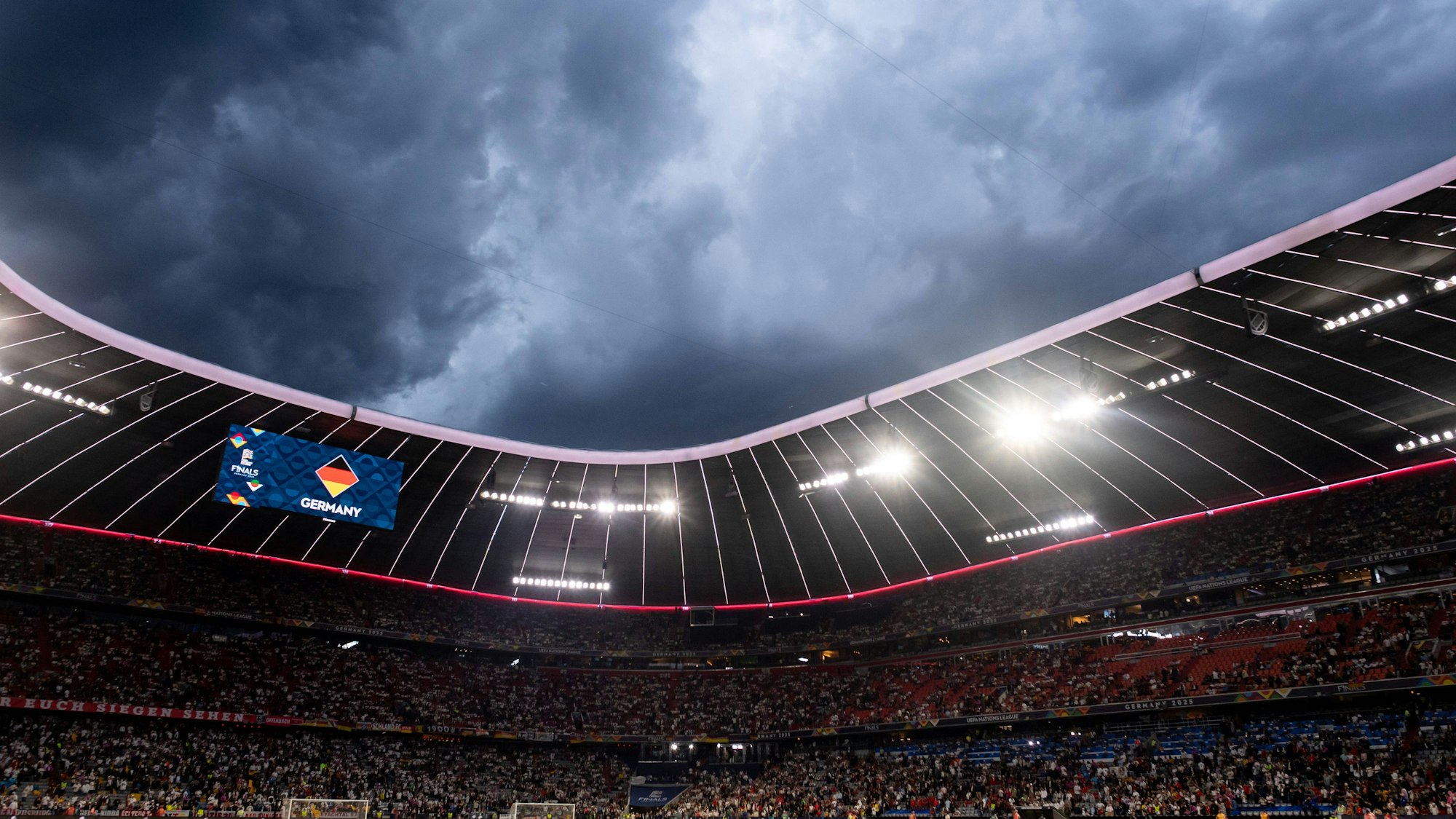 Fußballstadion mit Zuschauern unter dunklem Himmel