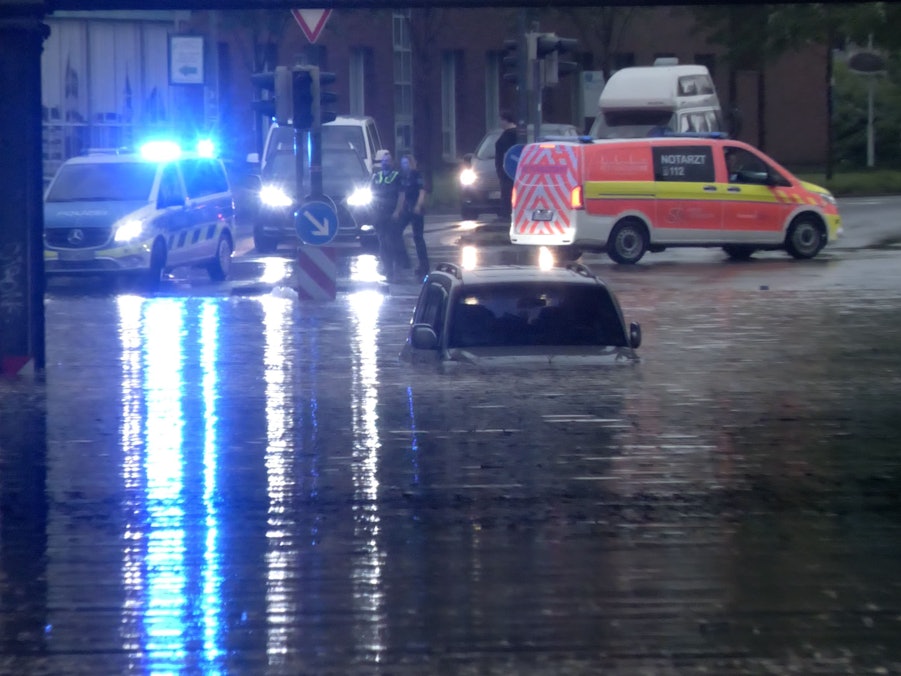 Ein Auto steht in Rheine in einer überfluteten Straße in einer Unterführung.