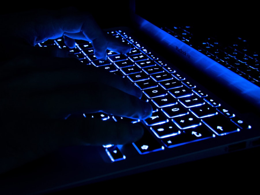 Hände tippen auf beleuchteter Tastatur