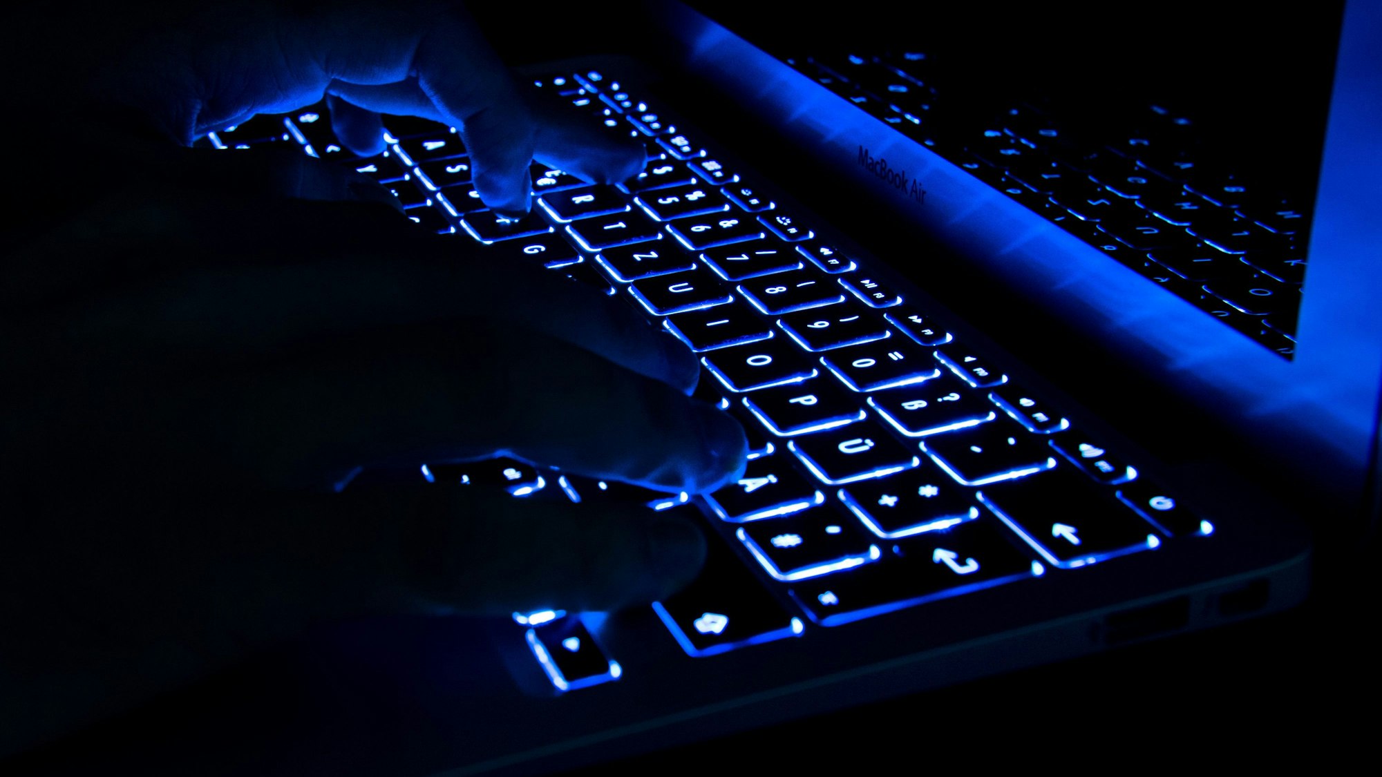 Hände tippen auf beleuchteter Tastatur