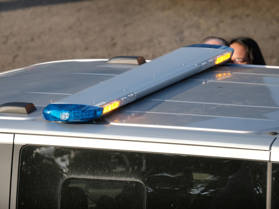 Polizeiauto mit Blaulichtbalken und Personen