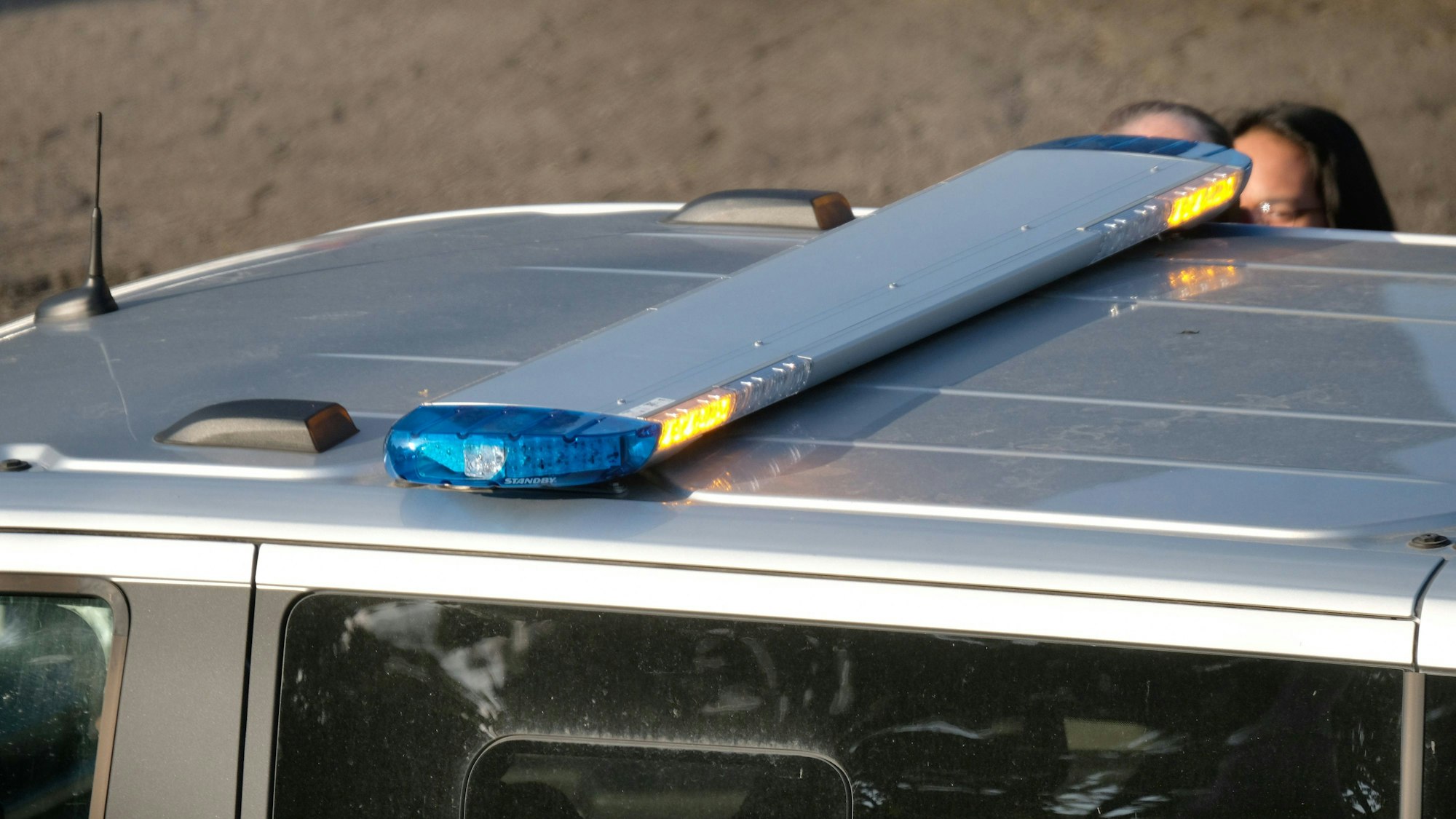 Polizeiauto mit Blaulichtbalken und Personen