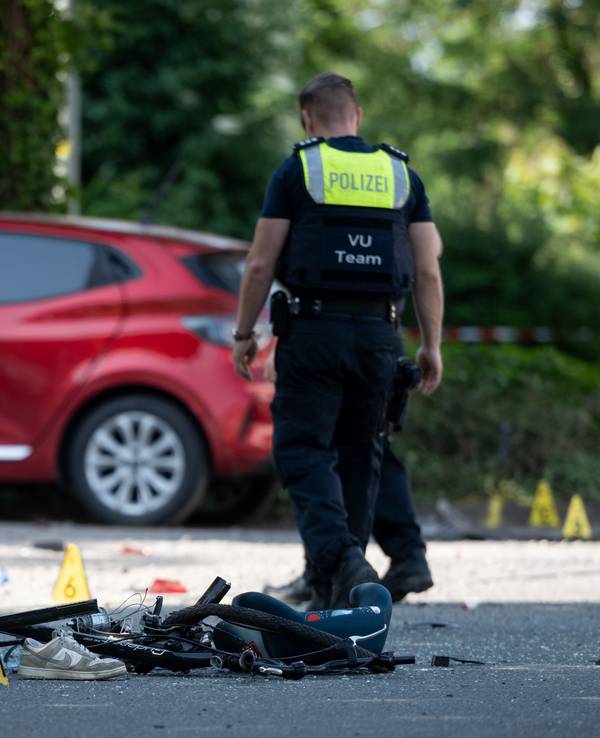 Ein Fahrrad liegt auf der Straße. Die Polizei sichert eine Unfallstelle, nachdem eine Autofahrerin in eine Kindergruppe gefahren ist.