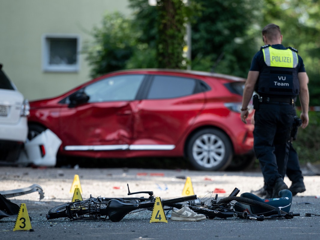 Ein Fahrrad liegt auf der Straße. Die Polizei sichert eine Unfallstelle, nachdem eine Autofahrerin in eine Kindergruppe gefahren ist.