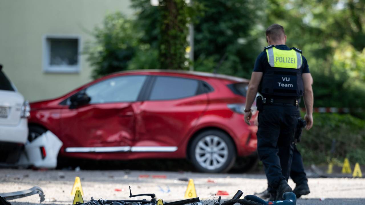 Ein Fahrrad liegt auf der Straße. Die Polizei sichert eine Unfallstelle, nachdem eine Autofahrerin in eine Kindergruppe gefahren ist.