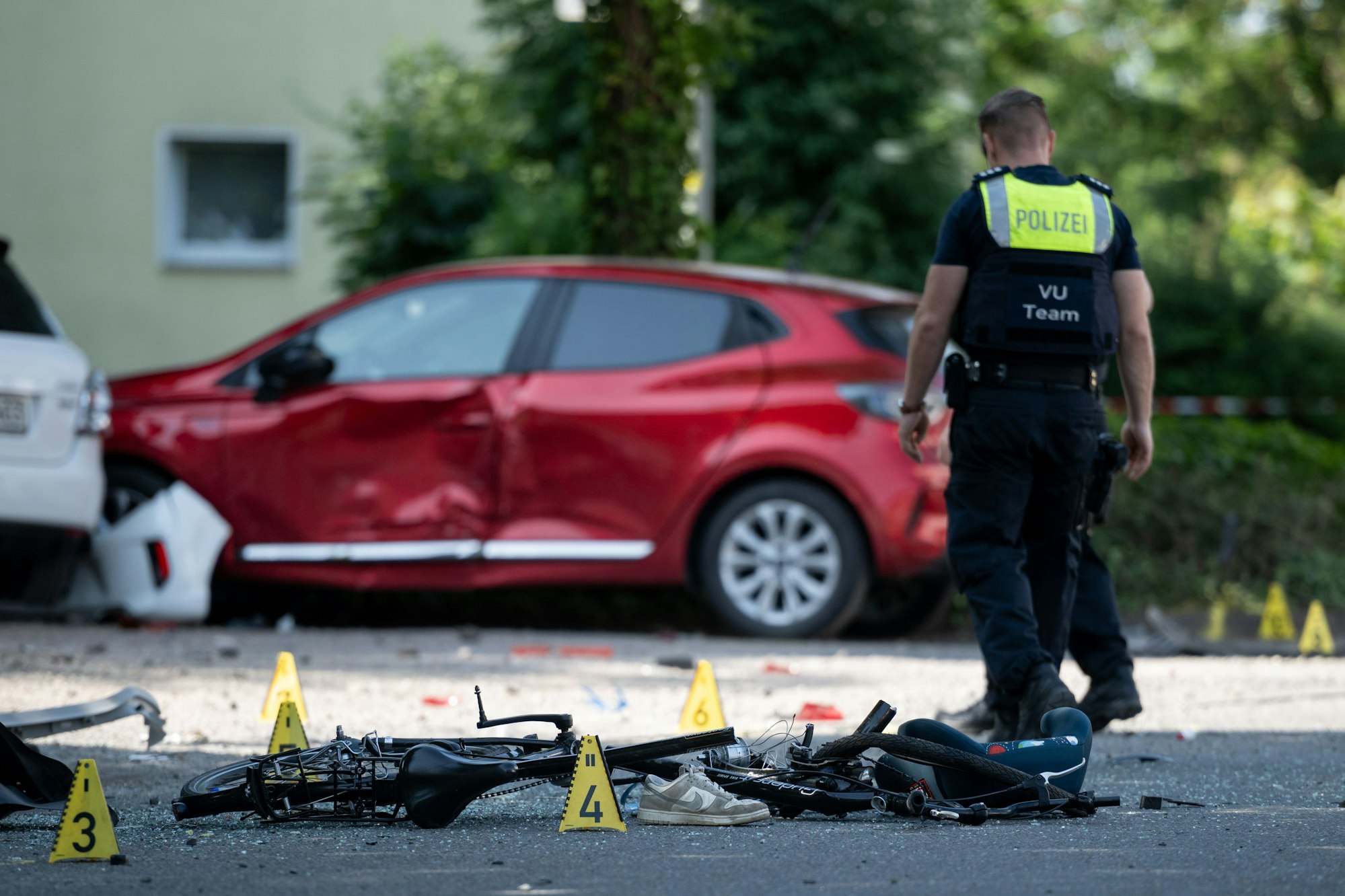 Ein Fahrrad liegt auf der Straße. Die Polizei sichert eine Unfallstelle, nachdem eine Autofahrerin in eine Kindergruppe gefahren ist.