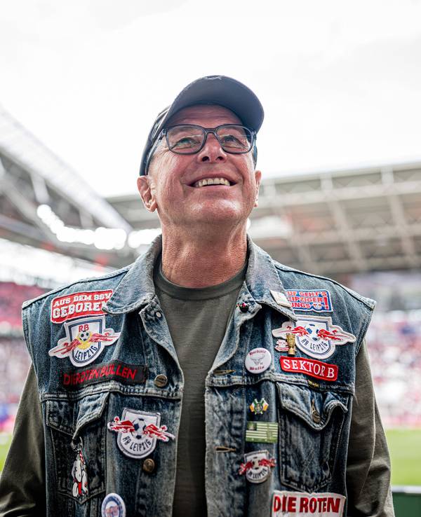 Ralf Rangnick mit Jeansweste mit Leipzig-Aufnähern vor der Fankurve.