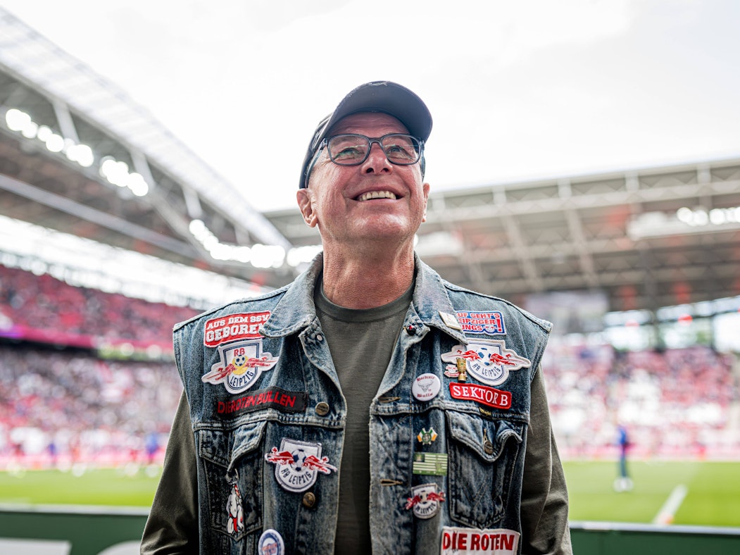Ralf Rangnick mit Jeansweste mit Leipzig-Aufnähern vor der Fankurve.