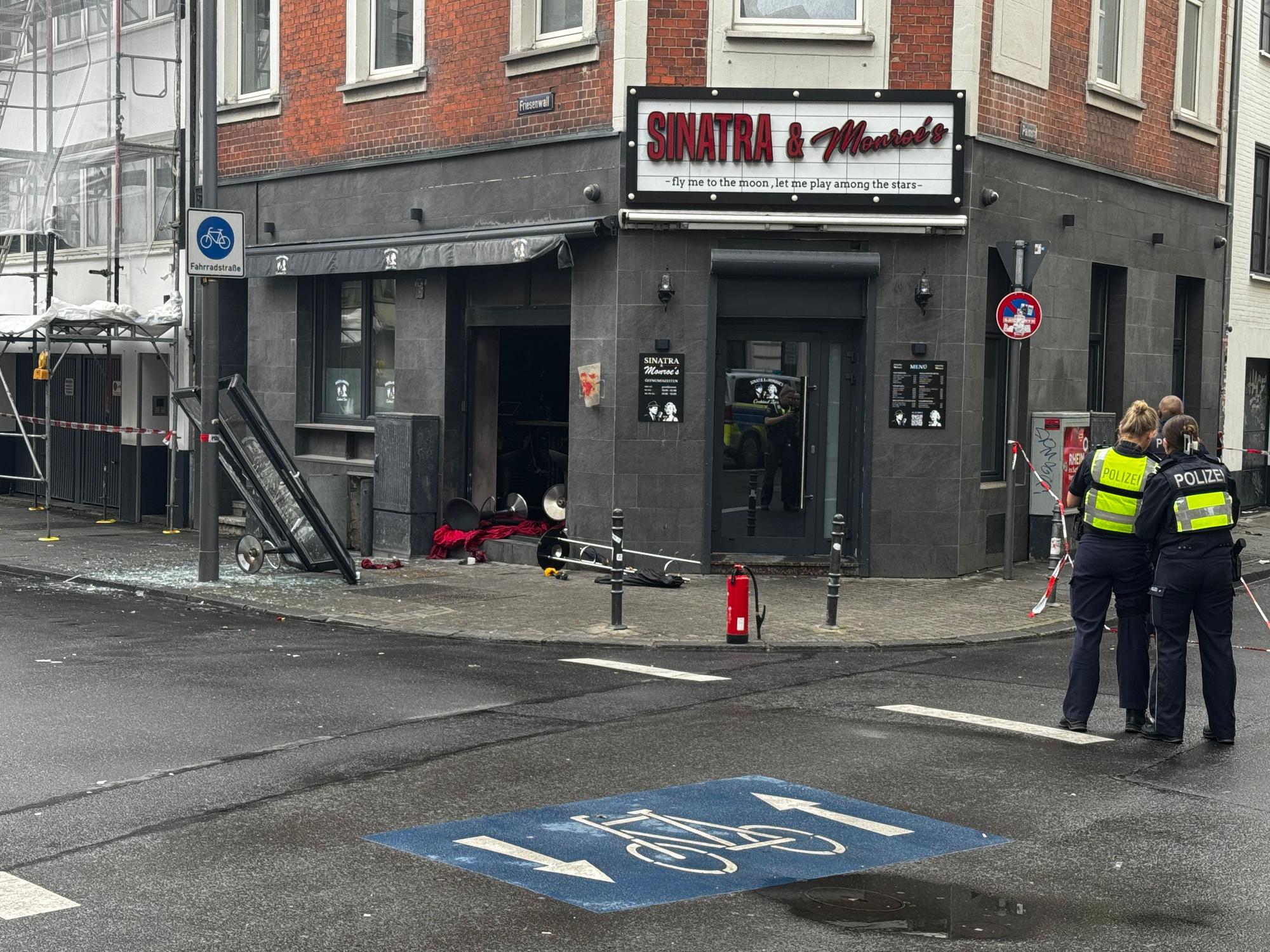 Blick auf die beschädigte Bar mit zerstörter Scheibe und Trümmern auf dem Boden.