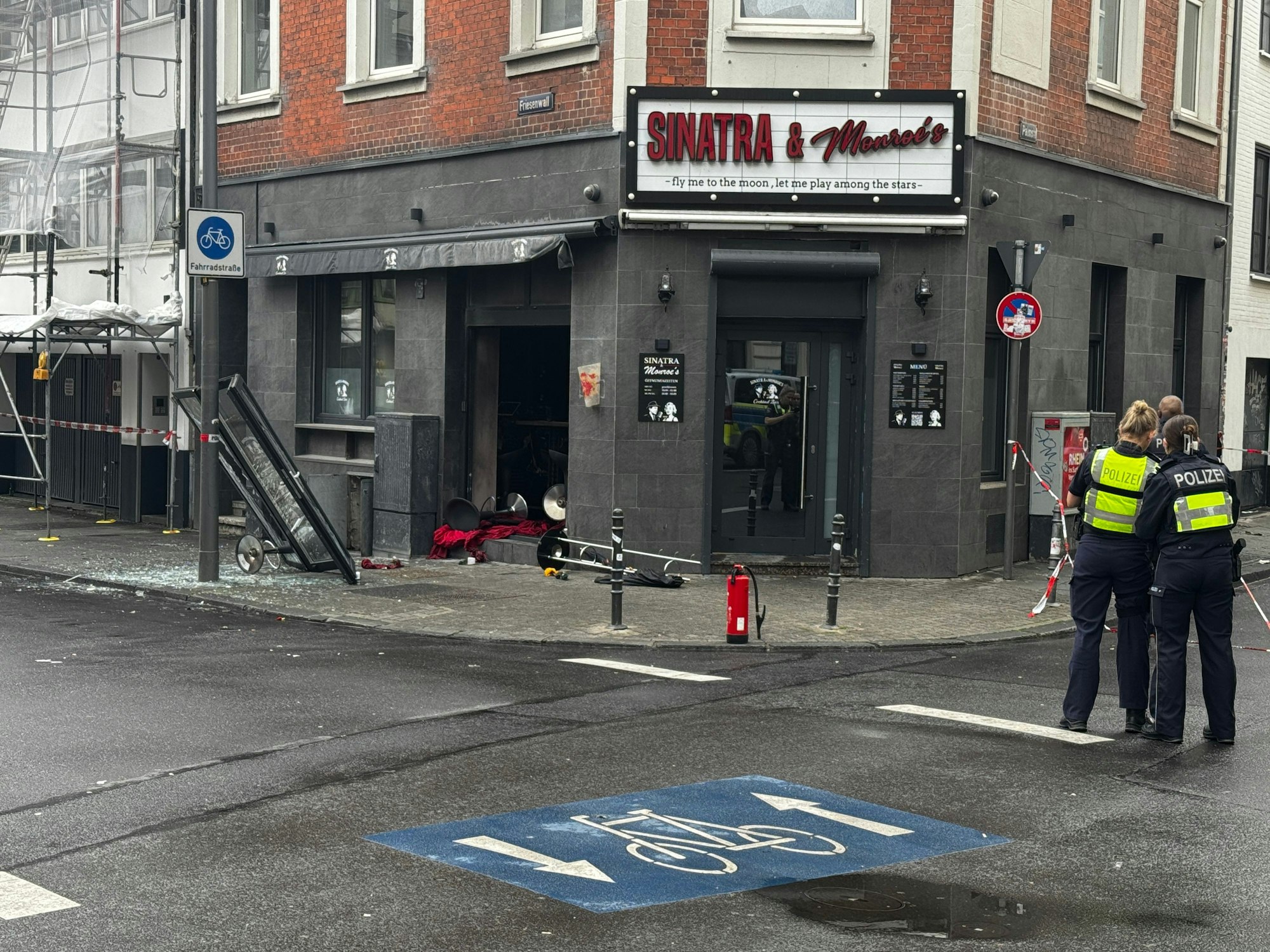 Blick auf die beschädigte Bar mit zerstörter Scheibe und Trümmern auf dem Boden.