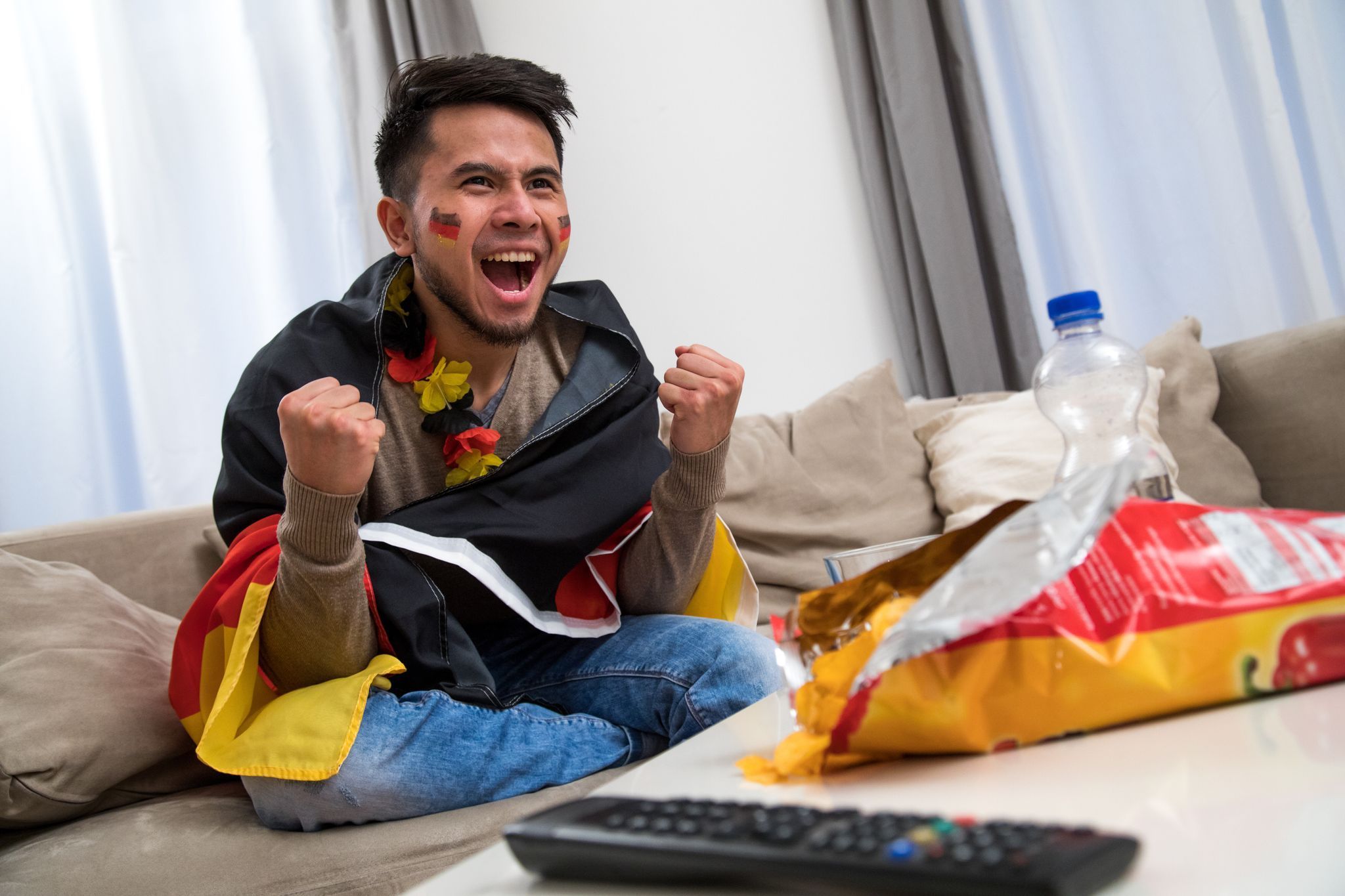 Ein Mann fiebert in WM-Deko vor dem Fernseher mit