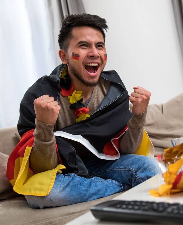 Ein Mann fiebert in WM-Deko vor dem Fernseher mit