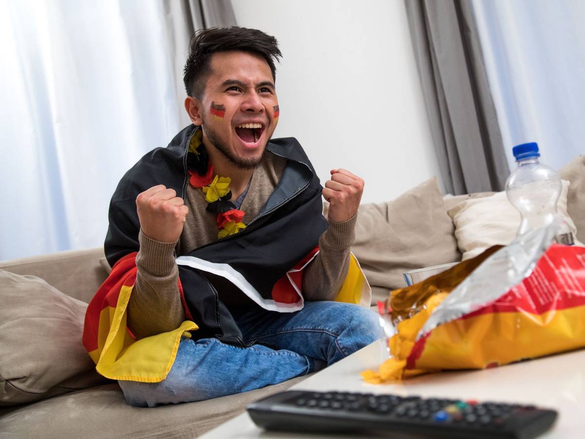 Ein Mann fiebert in WM-Deko vor dem Fernseher mit