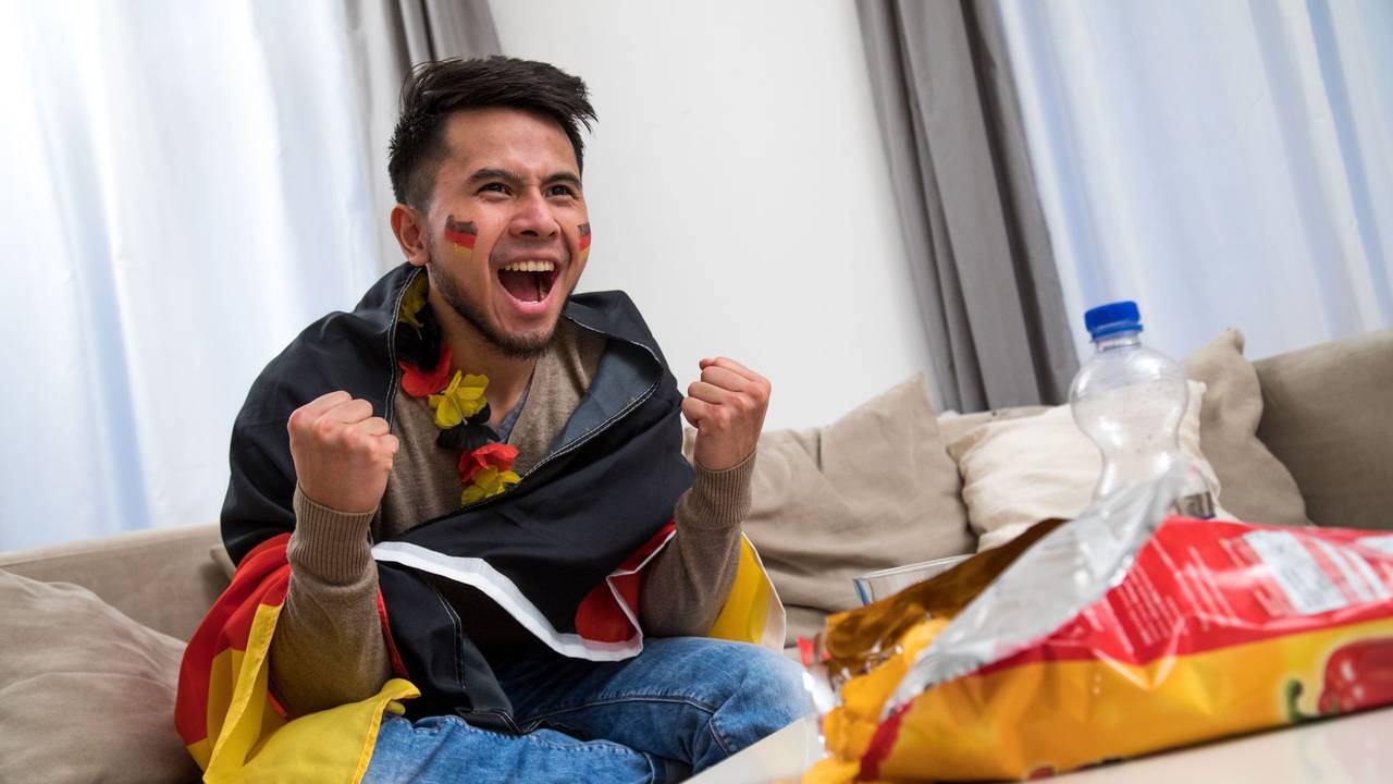 Ein Mann fiebert in WM-Deko vor dem Fernseher mit