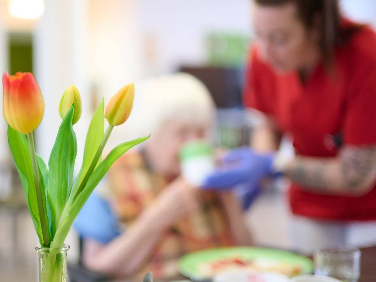 Eine Pflegekraft unterstützt eine Seniorin