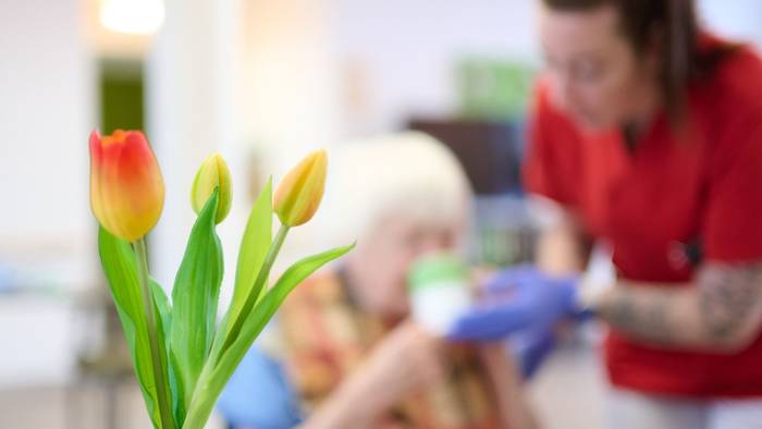 Eine Pflegekraft unterstützt eine Seniorin