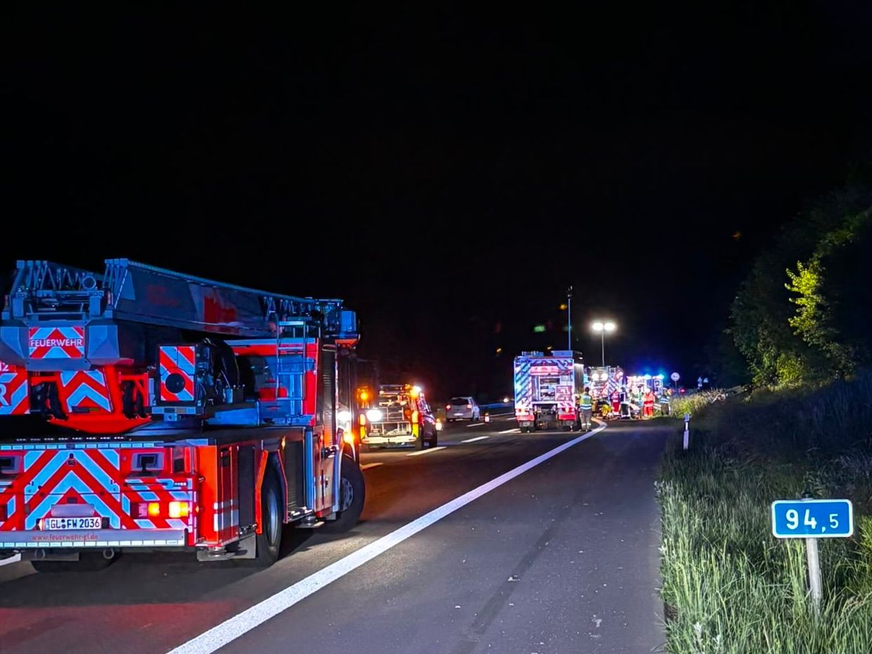 Einsatzfahrzeuge von Feuerwehr und Rettungsdienst stehen nachts auf einer Autobahn.