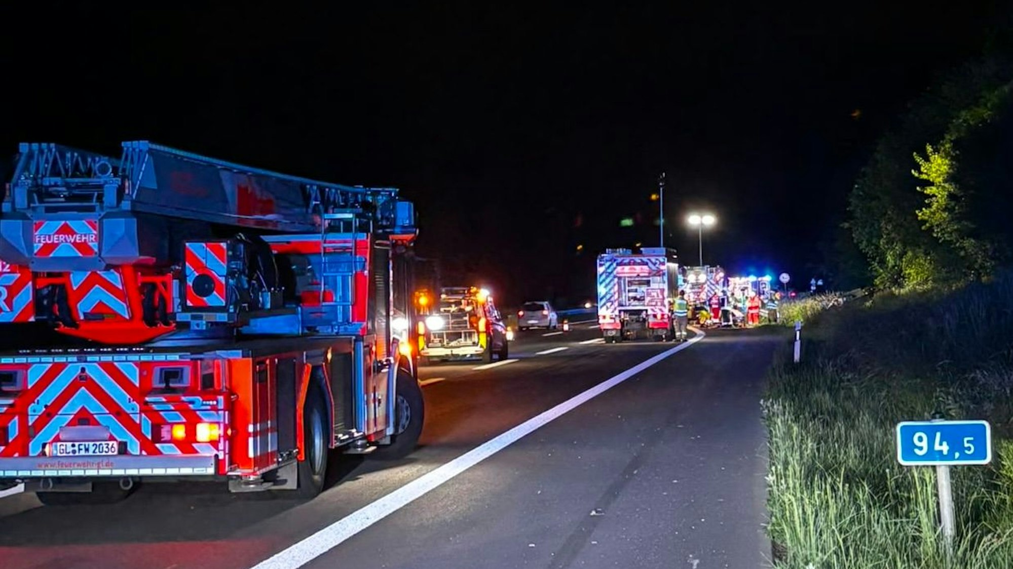 Einsatzfahrzeuge von Feuerwehr und Rettungsdienst stehen nachts auf einer Autobahn.